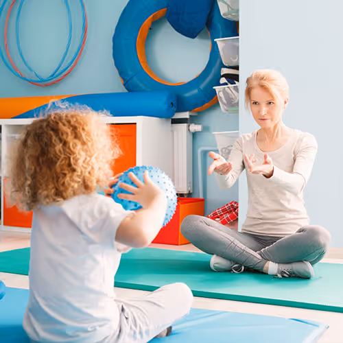 dziecko rzuca piłką podczas fizjoterapii