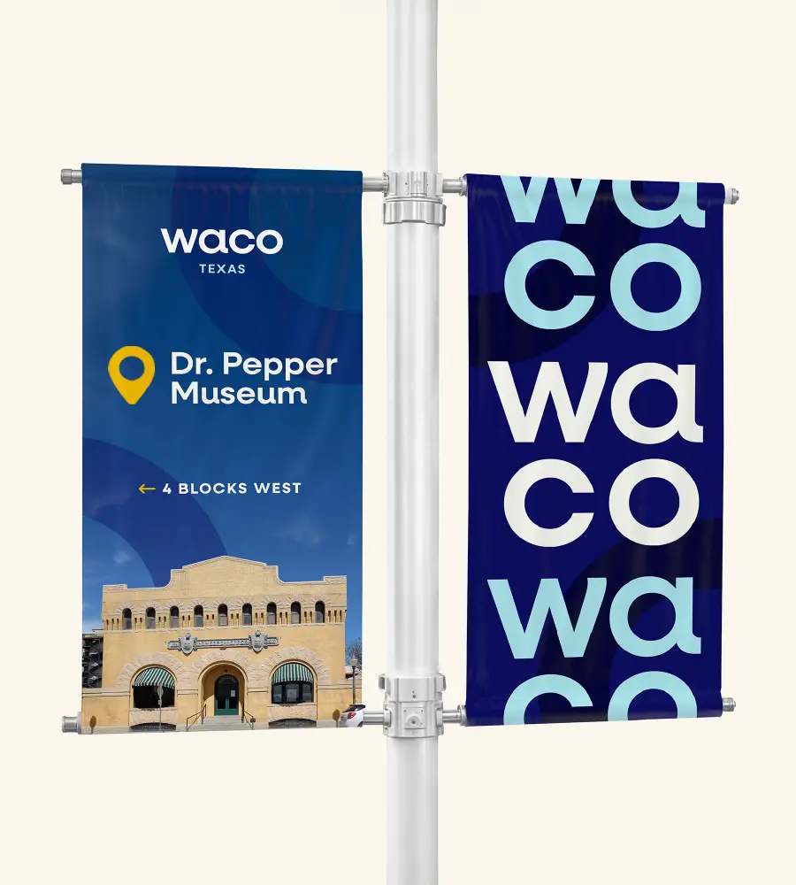 Street pole with two banners, one showing Waco Texas and directions to Dr. Pepper Museum with museum building image, the other repeating 'waco' text in blue tones.