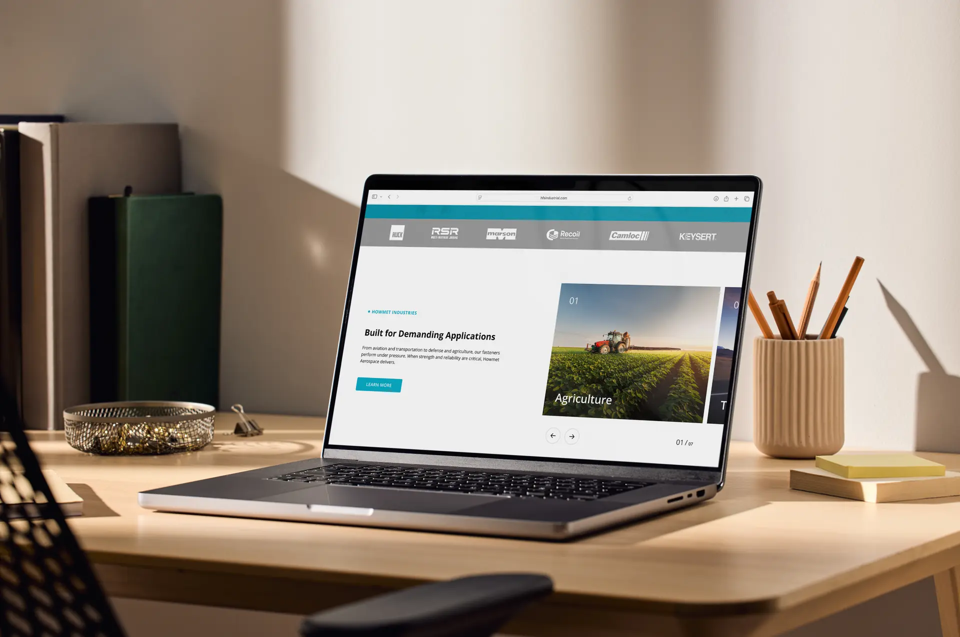 Laptop on a wooden desk displaying a website homepage with agriculture industry content.