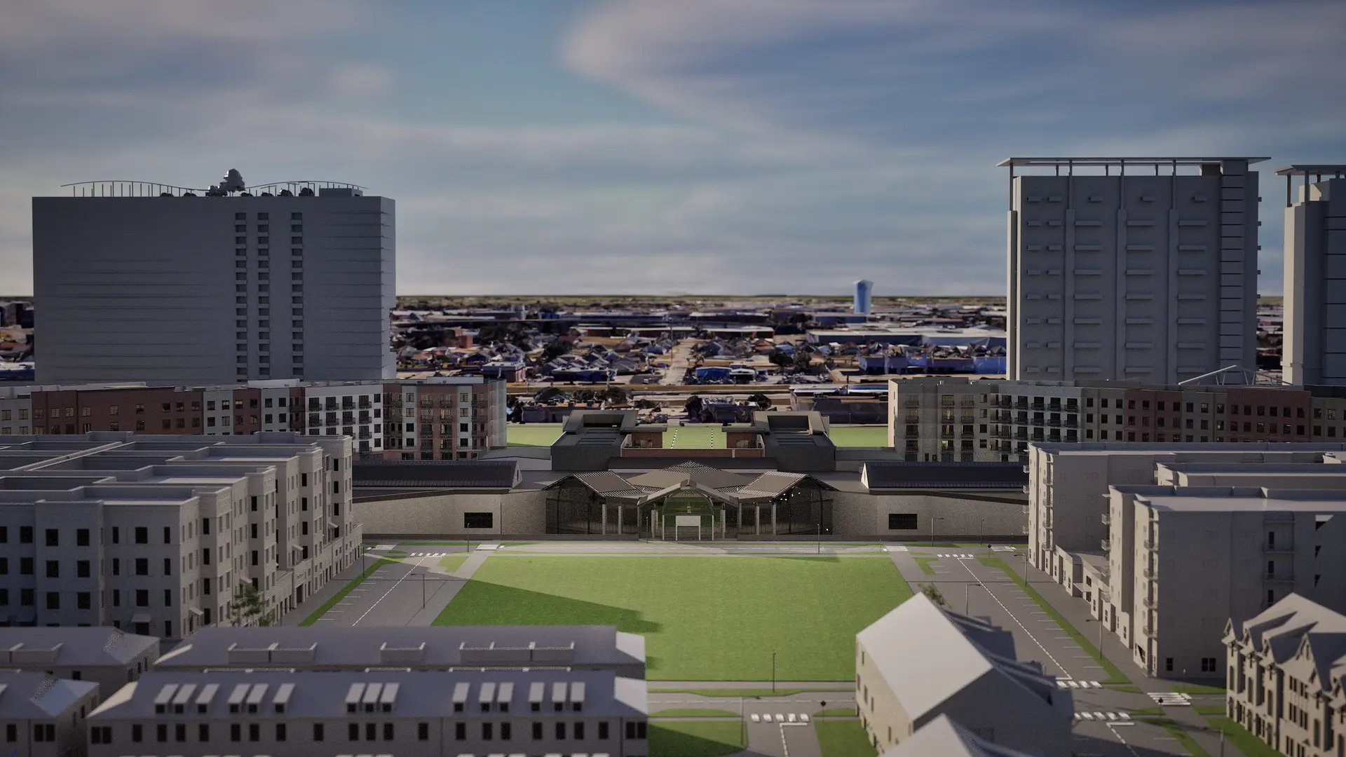 Urban area with multiple modern apartment buildings surrounding a large grassy courtyard under a partly cloudy sky.