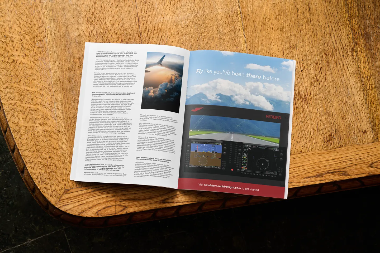 Open magazine on wood table with flight simulation ad showing cockpit and sky view.