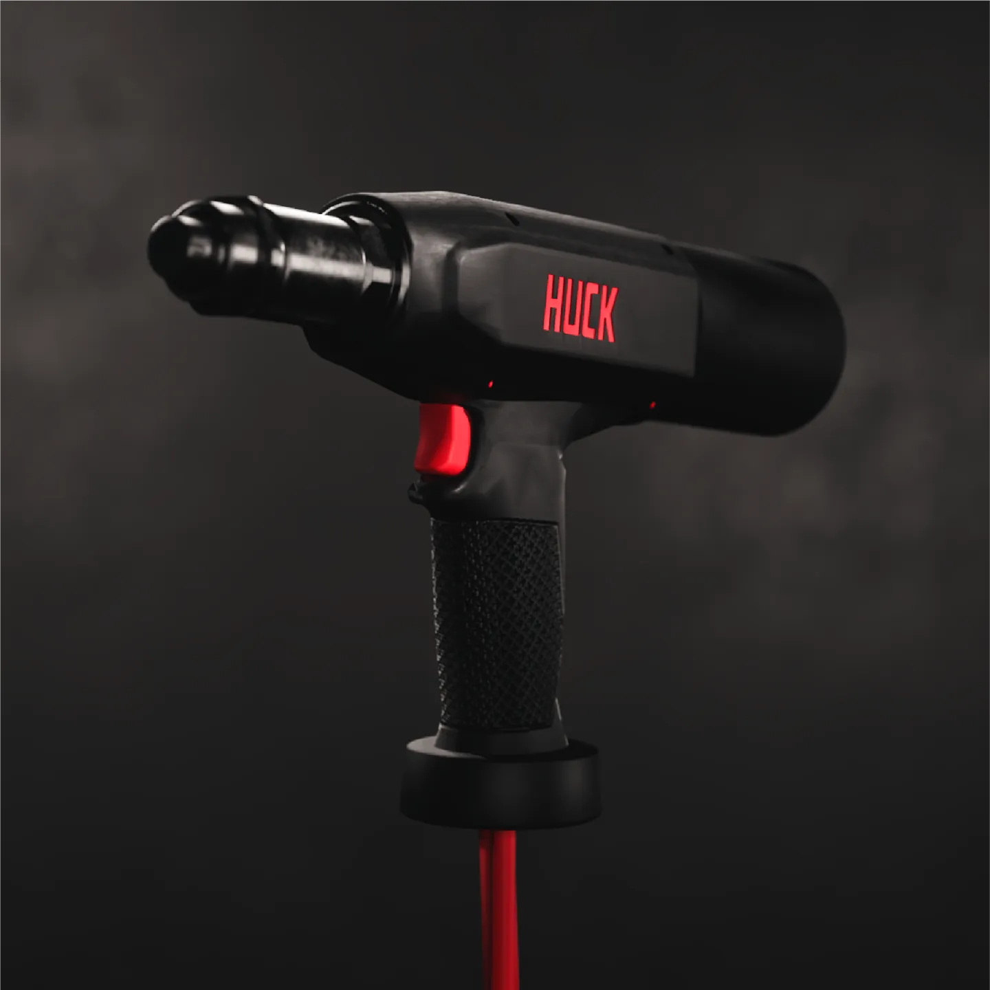 Black power tool with red trigger and the word 'HUCK' in red on its body against a dark background.