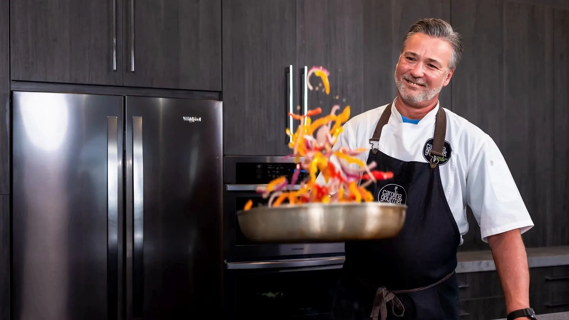 Chef Peter Olsacher tossing vegetable in a pan for a catering event