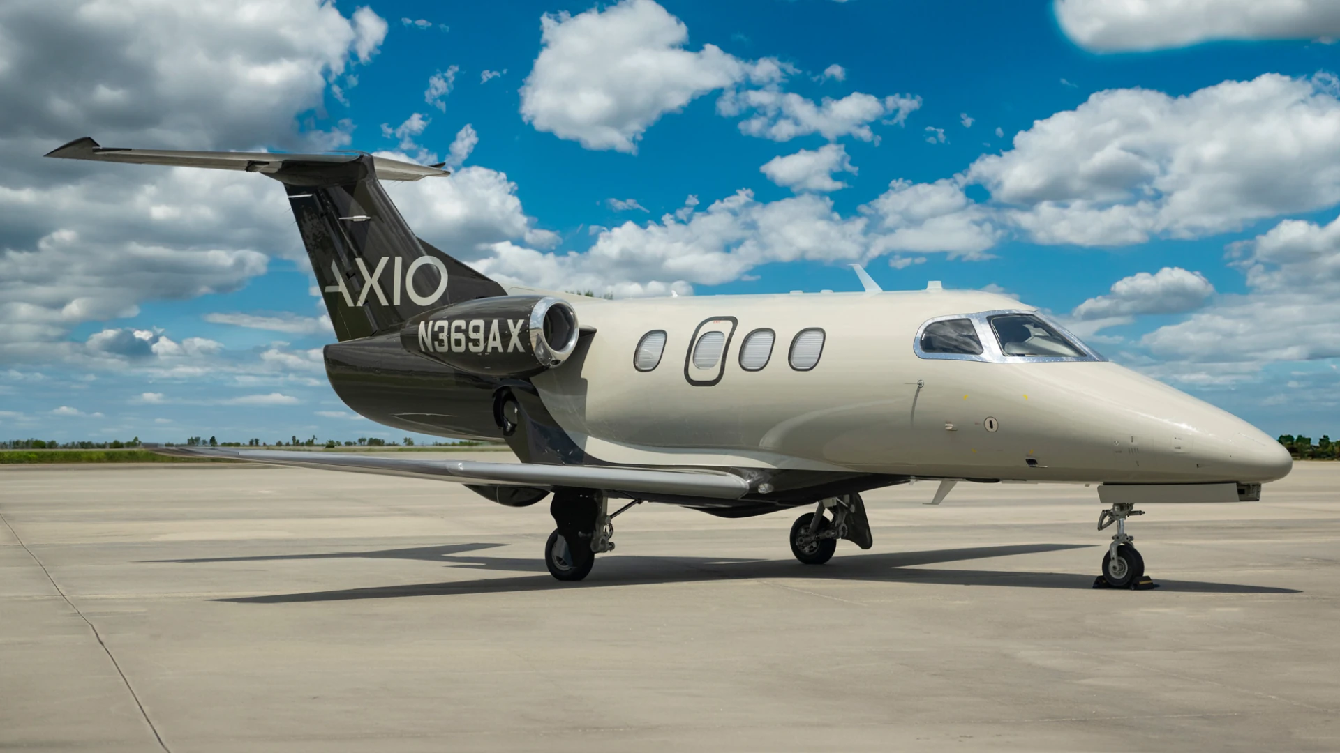 Axio-branded private jet on an airport apron beneath a blue sky