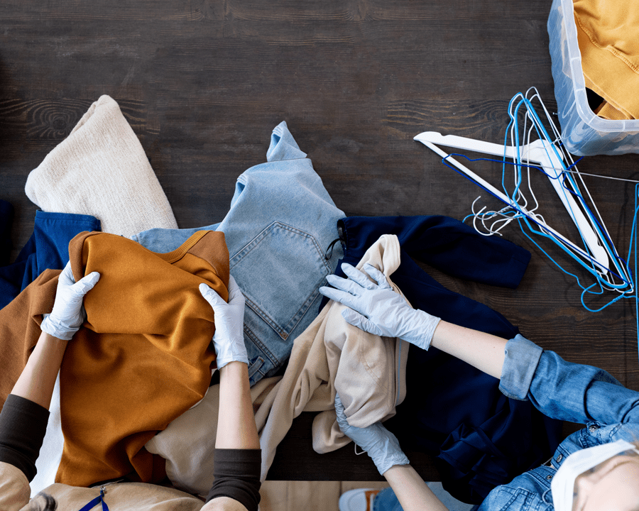 gloved hands sorting through clothing on a table