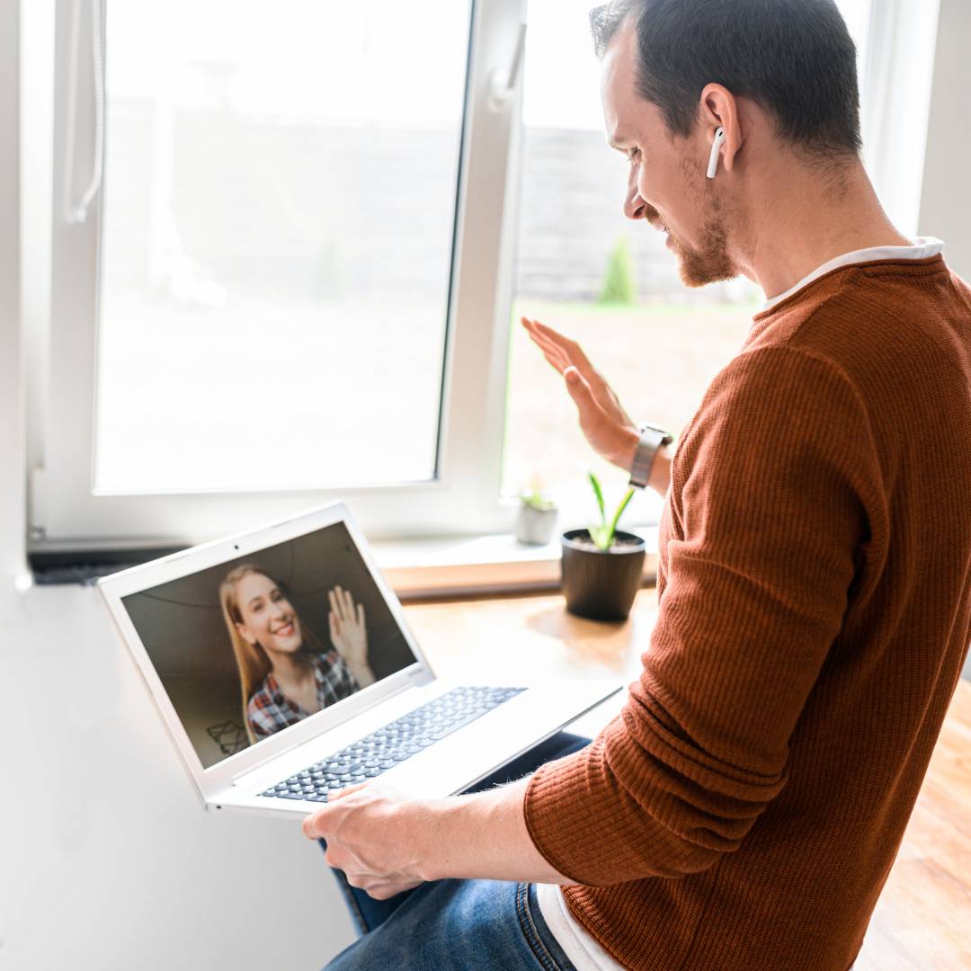 HAMMOQ virtual demo - a man waves to the woman he is on a video conference call on his laptop with, and she waves back.
