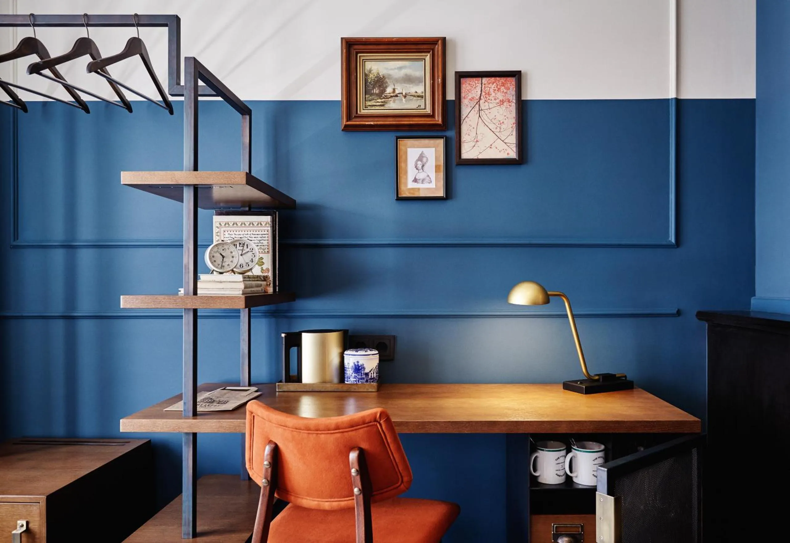 The Hoxton Amsterdam workspace with rust leather chair, wooden desk and framed art on blue panelling