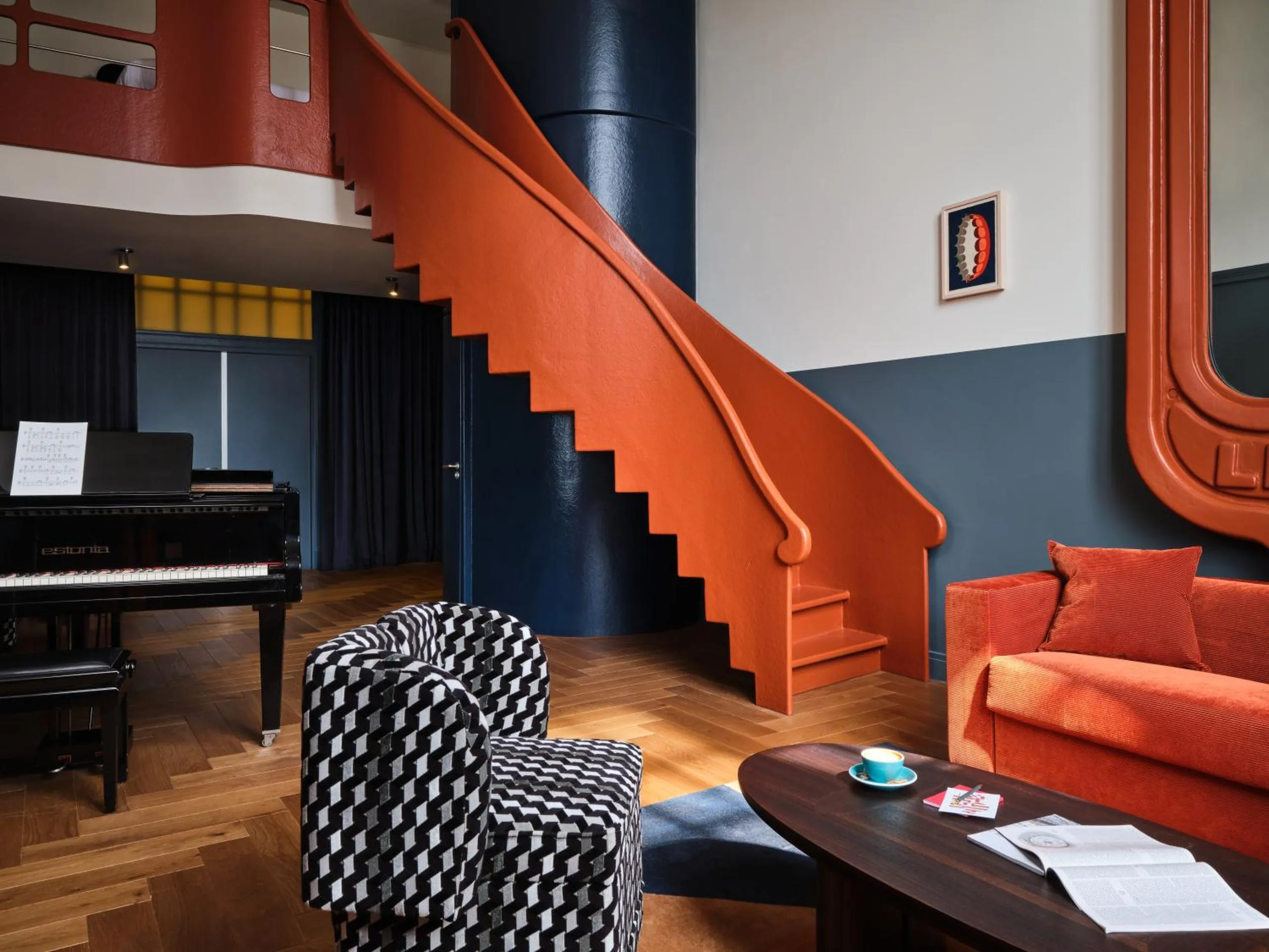 The Hoxton Lloyd Amsterdam suite with sculptural orange staircase, grand piano and herringbone parquet floor