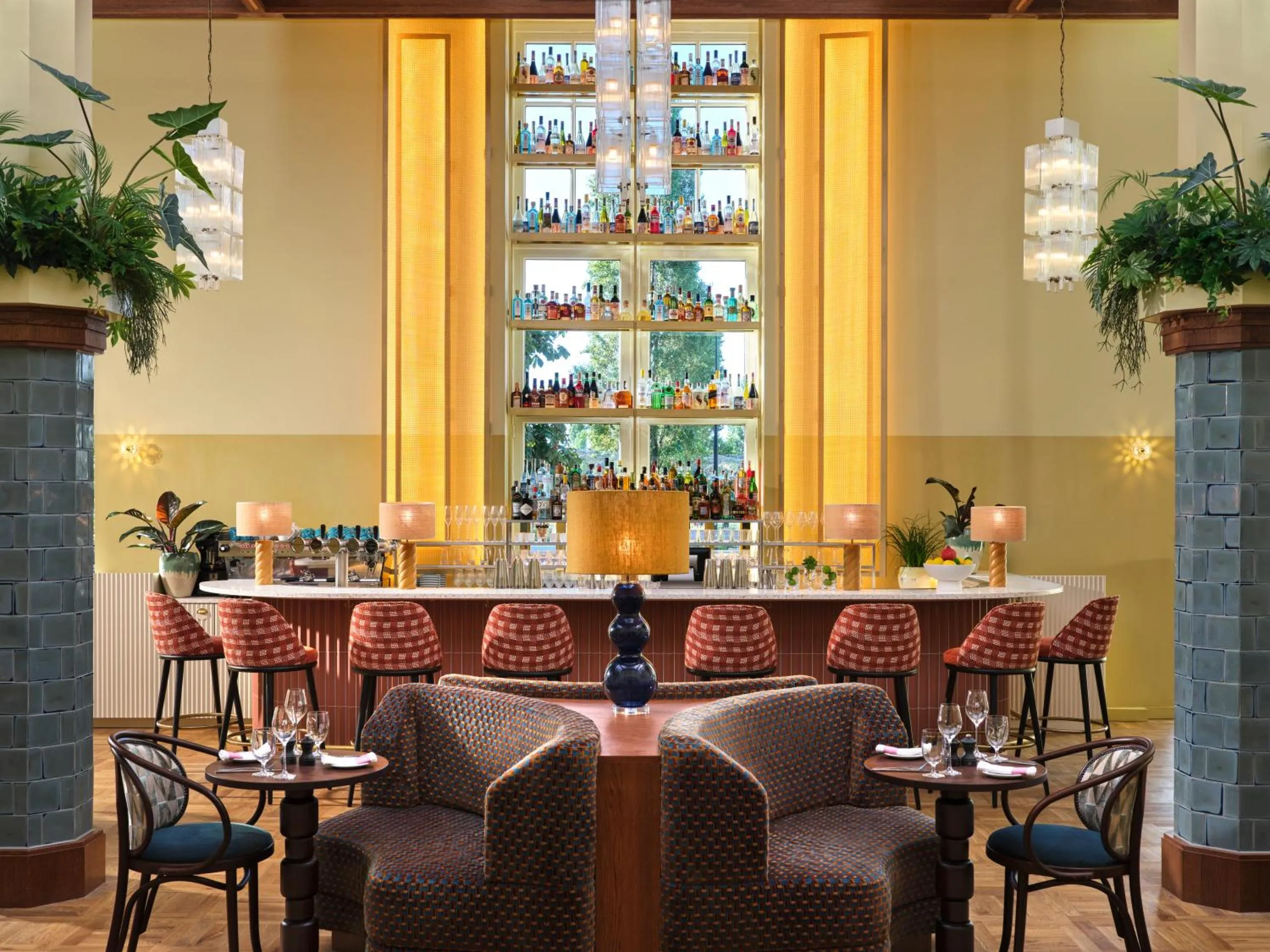 Breman Brasserie at The Hoxton Lloyd Amsterdam with illuminated bottle wall, glass chandeliers and red checked stools