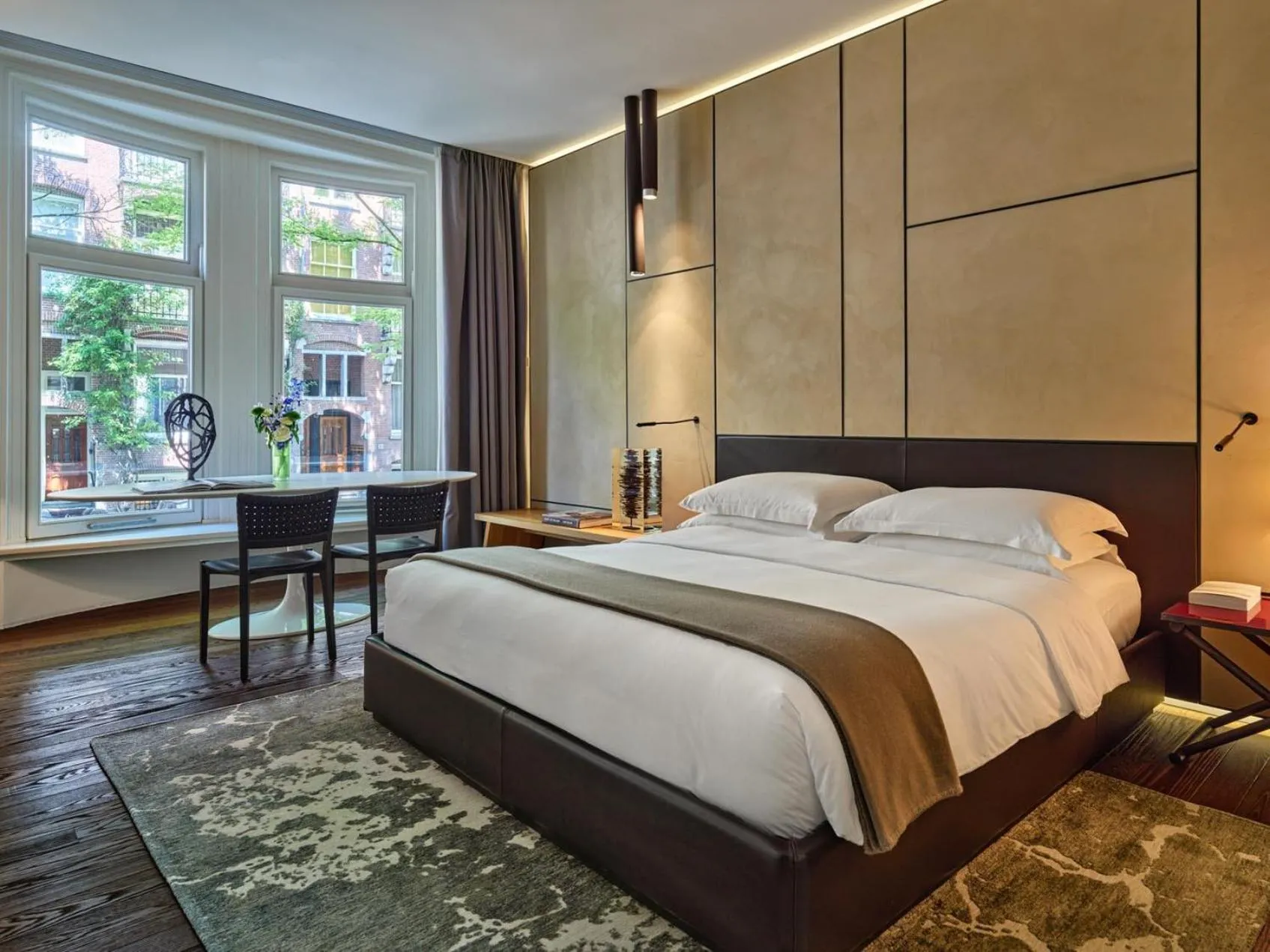 Conservatorium Amsterdam guest room with leather-panelled headboard wall, neutral tones and bay window