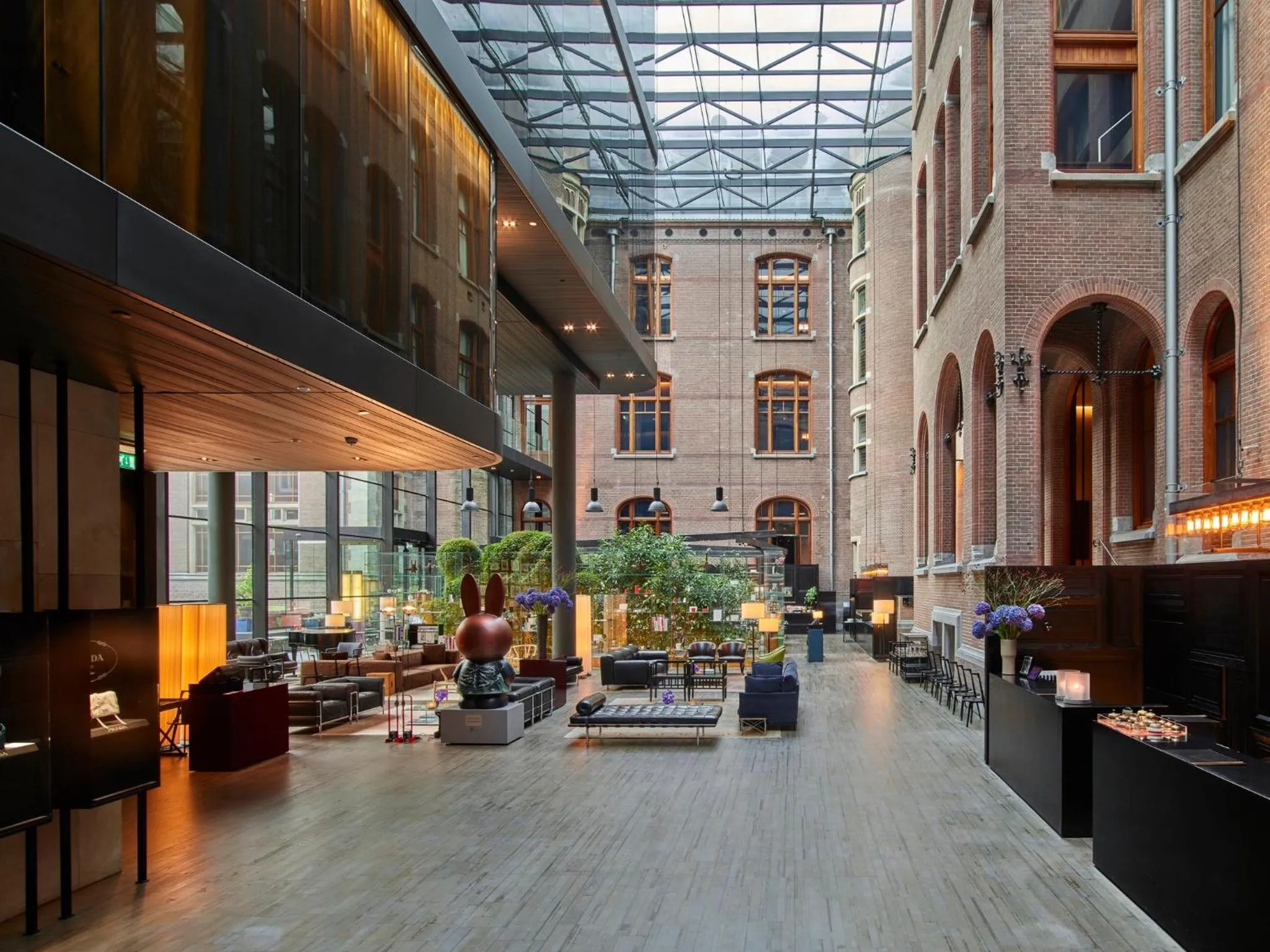 Conservatorium Amsterdam glass-roofed atrium lobby with red brick walls and a Miffy sculpture