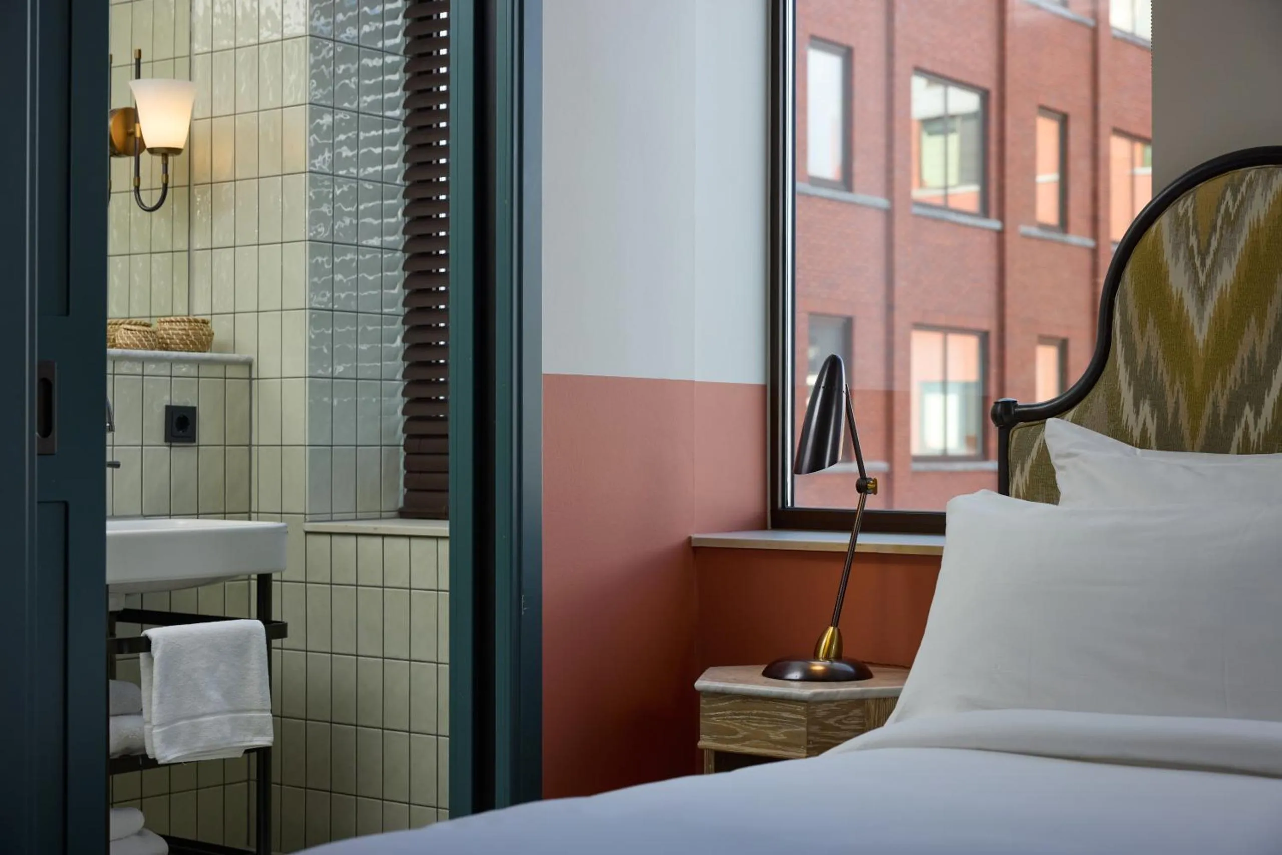 The July Boat & Co room with sage tiled bathroom, terracotta walls and chevron upholstered headboard