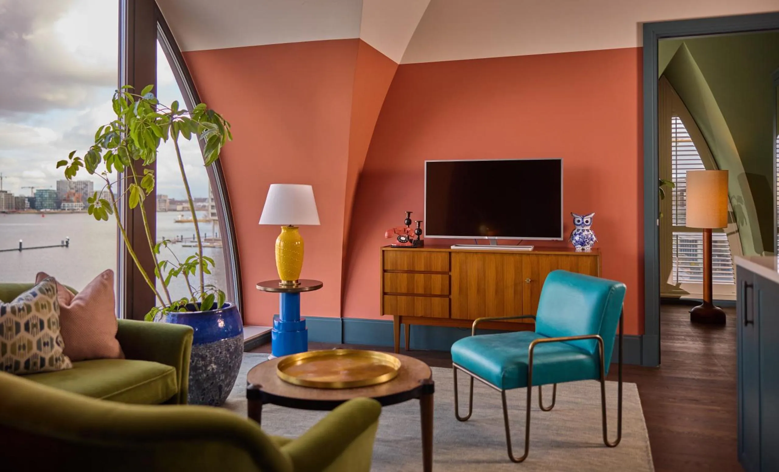 The July Boat & Co suite with arched window, IJ-river view, terracotta walls and mid-century furniture