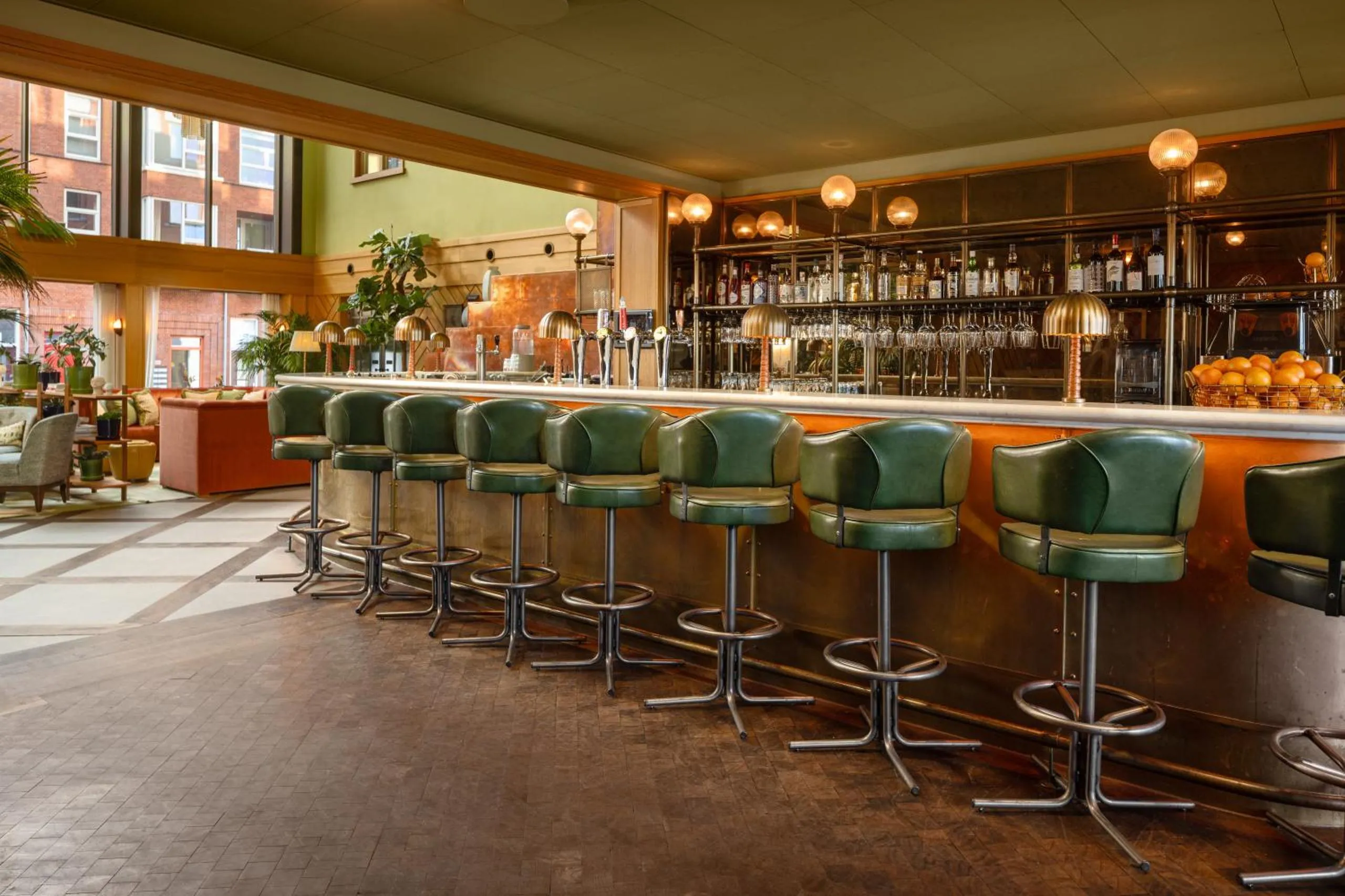 Vessel bar at The July Boat & Co with copper bar front, green leather stools and globe lamps