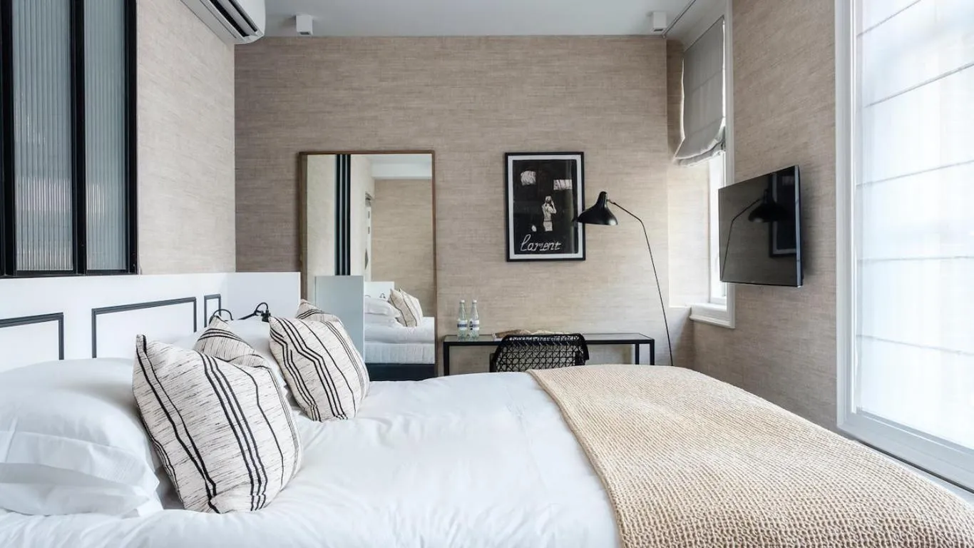Morgan & Mees Amsterdam bedroom with grasscloth walls, freestanding mirror and monochrome framed art
