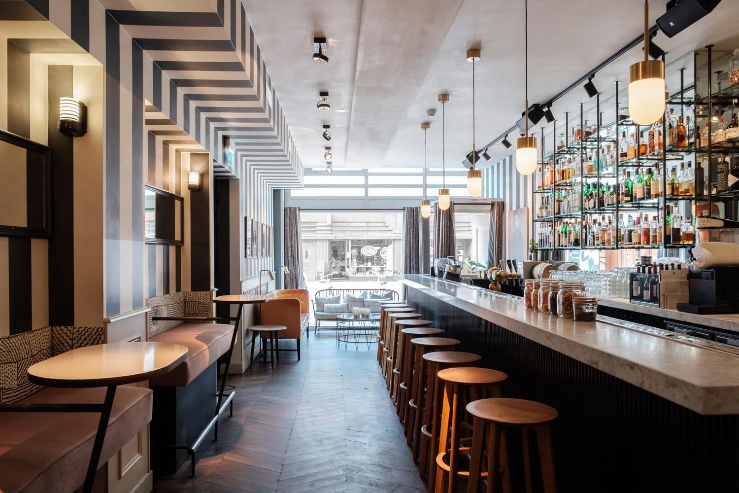 Restaurant and bar at Morgan & Mees Amsterdam with striped wallpaper, marble counter and globe pendants