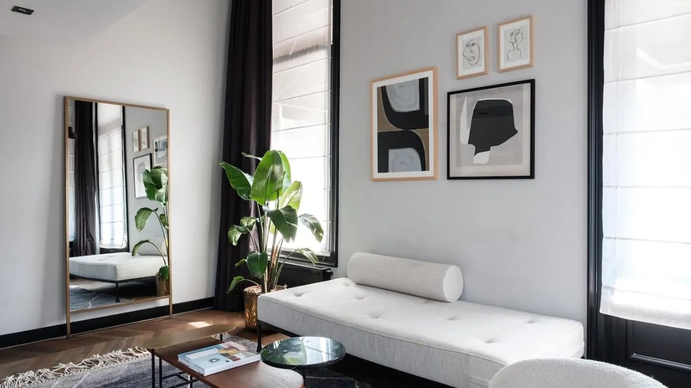 Morgan & Mees Amsterdam sitting area with white daybed, monochrome gallery wall and brass-framed mirror