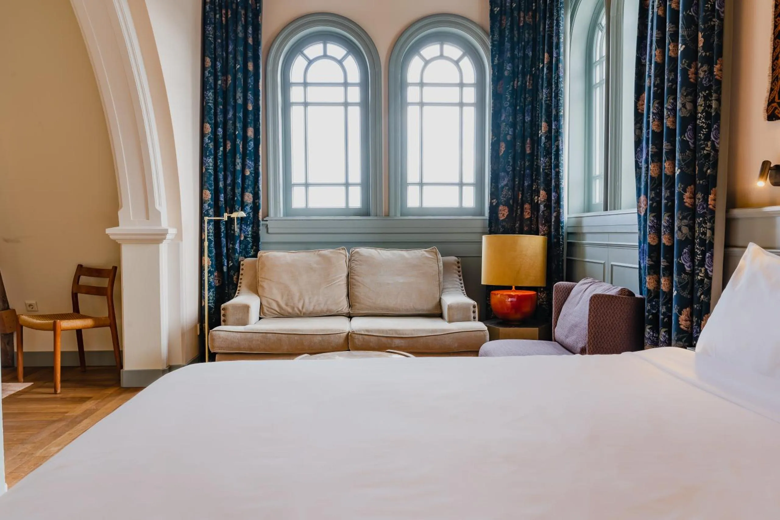 Hotel Mercier suite with arched leaded windows, floral curtains and velvet sofa