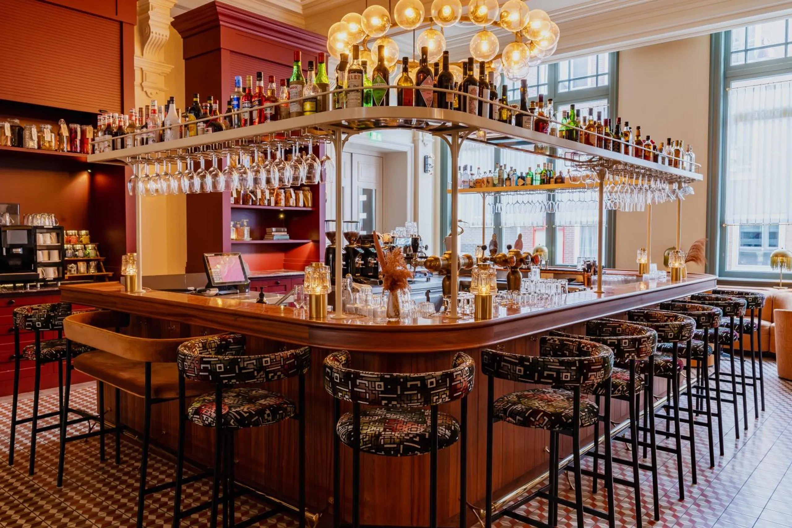 Cocktail bar at Hotel Mercier with timber counter, globe chandelier and patterned bar stools