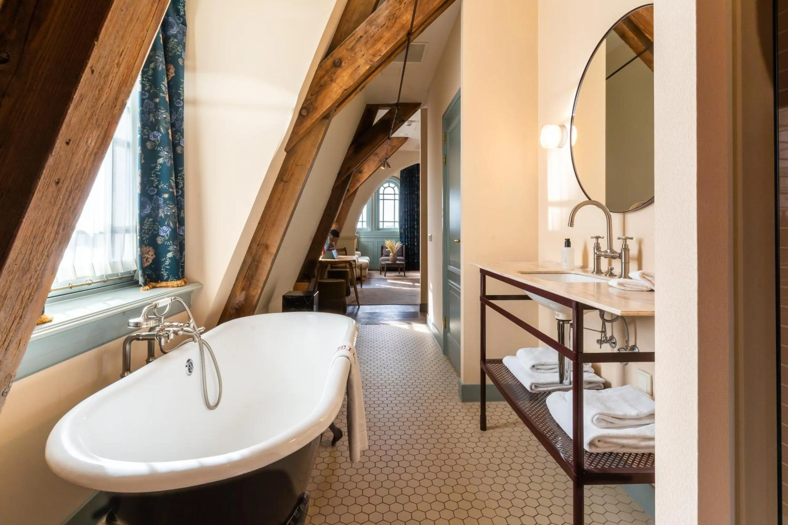 Hotel Mercier bathroom with exposed timber rafters, claw-foot tub and hexagonal floor tiles