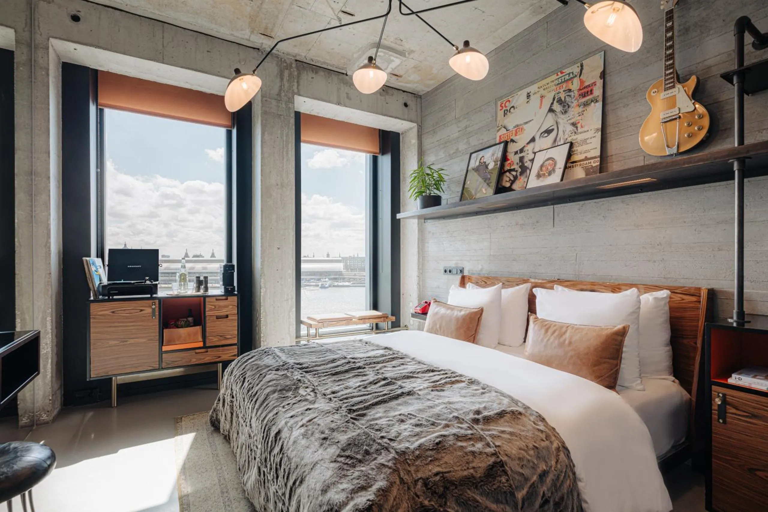 Sir Adam Hotel suite with raw concrete walls, IJ-river view, vintage record player and a Gibson guitar