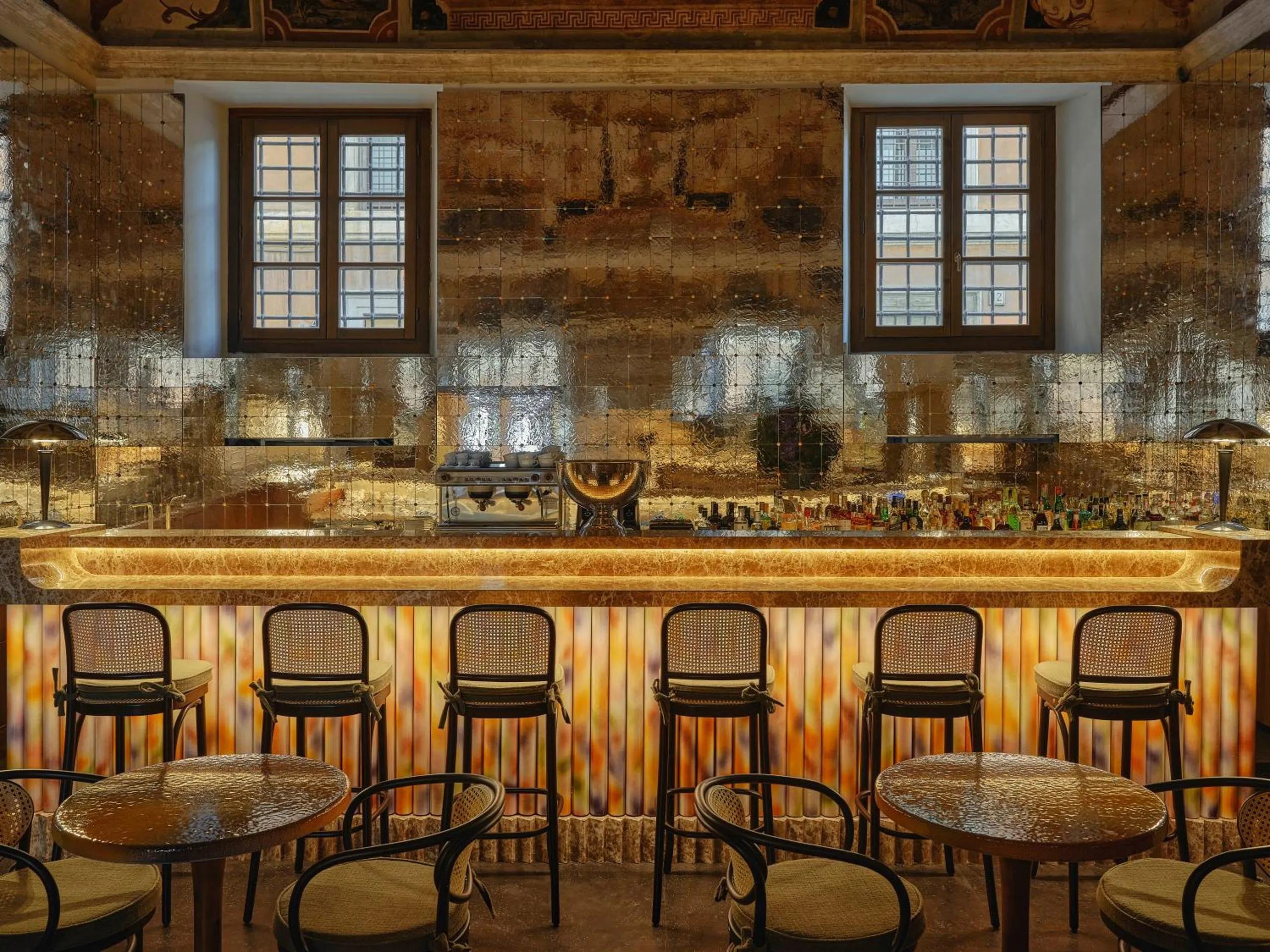 Bar della Musa at Palazzo Talìa with mirrored gold tile walls, marble counter and cane bentwood stools