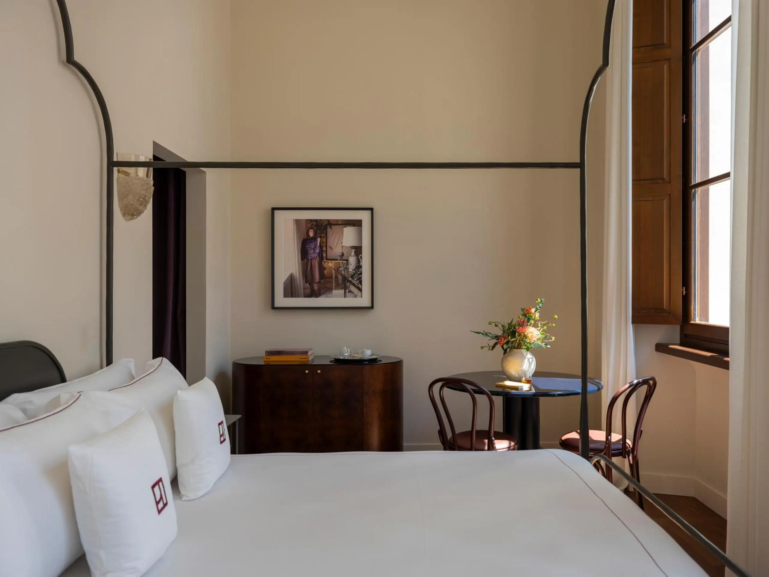 Palazzo Talìa bedroom with iron four-poster bed, walnut credenza and bistro table by the window