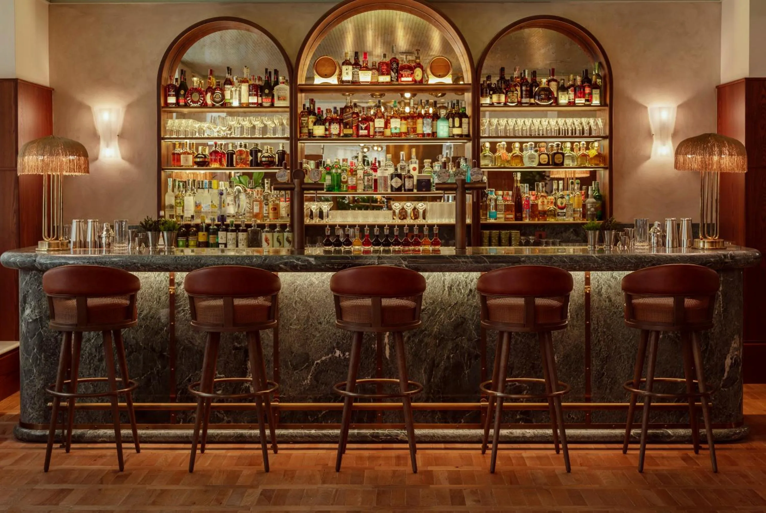 The Hoxton Rome cocktail bar with green marble counter, arched bottle alcoves and fringed brass lamps