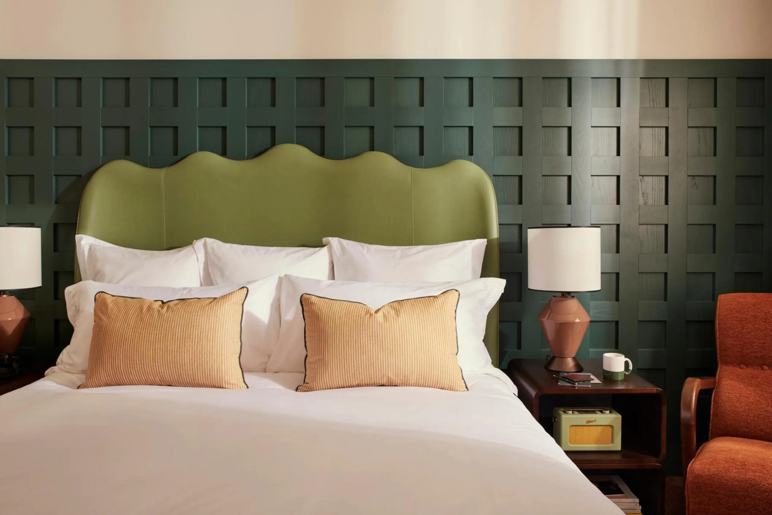 The Hoxton Rome bedroom with green panelled wall, wave-shaped leather headboard and vintage radio
