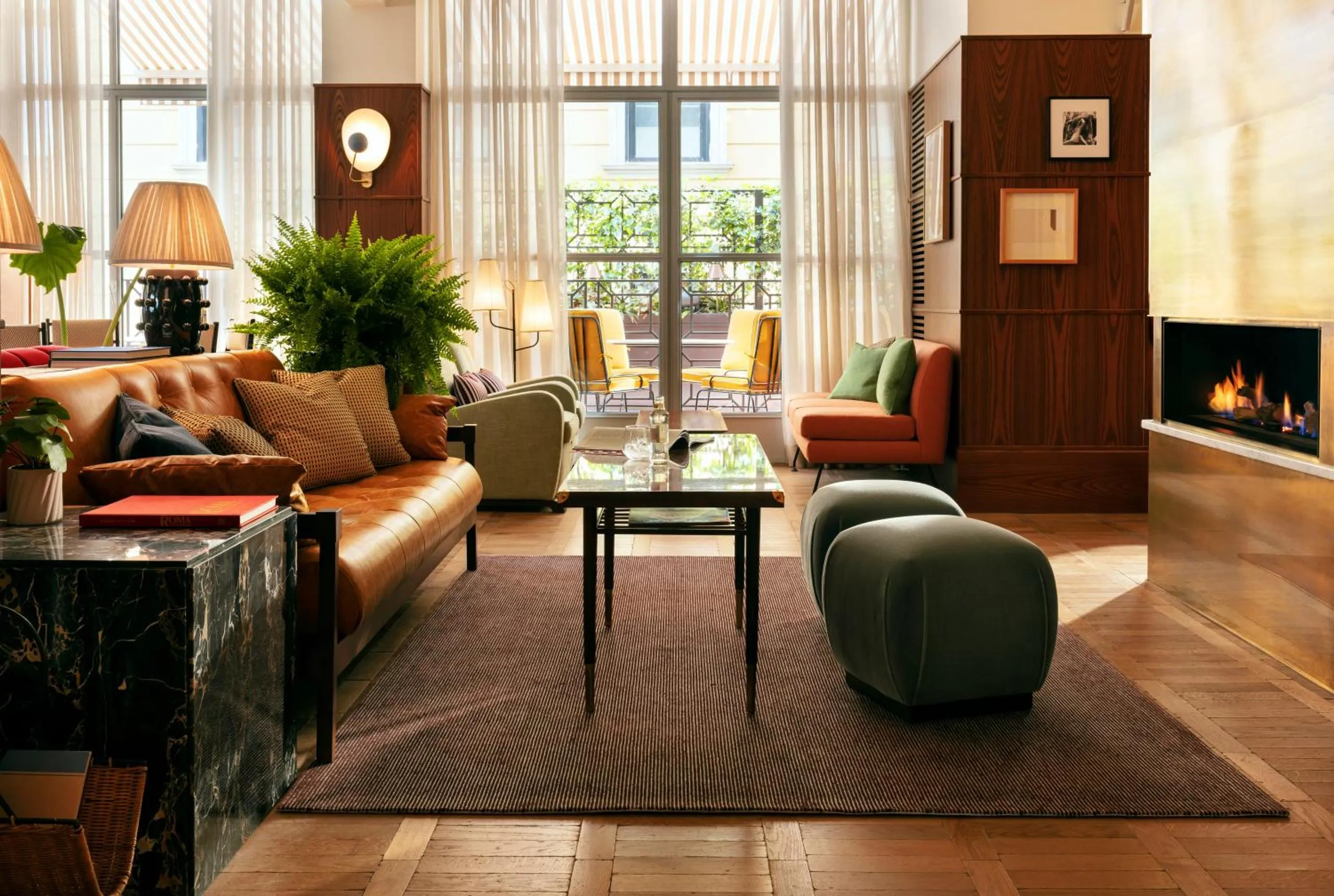 The Hoxton Rome lobby lounge with tan leather sofa, brass fireplace and herringbone parquet floor