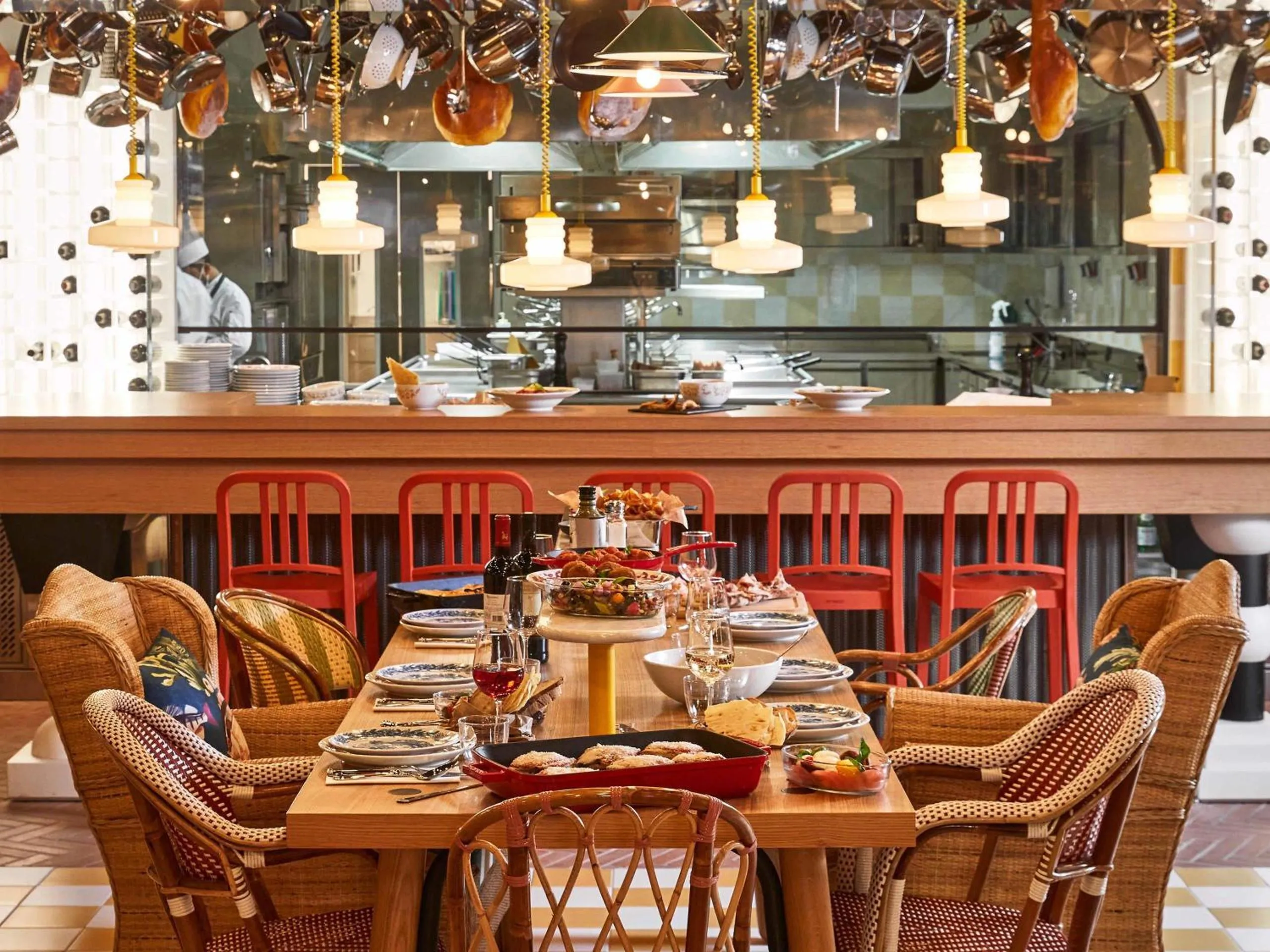 Mama Pizzeria at Mama Shelter Roma with island bar, hanging copper pots and red counter stools