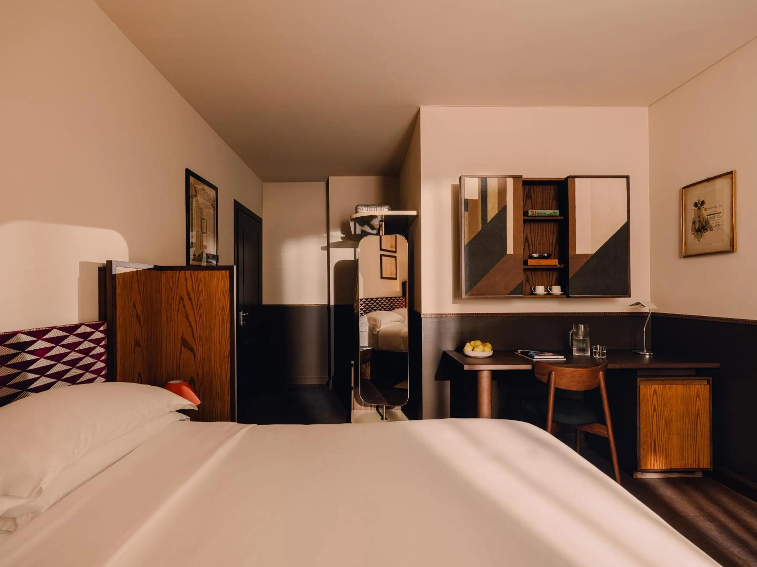 Aethos Milan guest room with burgundy harlequin headboard, oak panelling, geometric artwork and writing desk