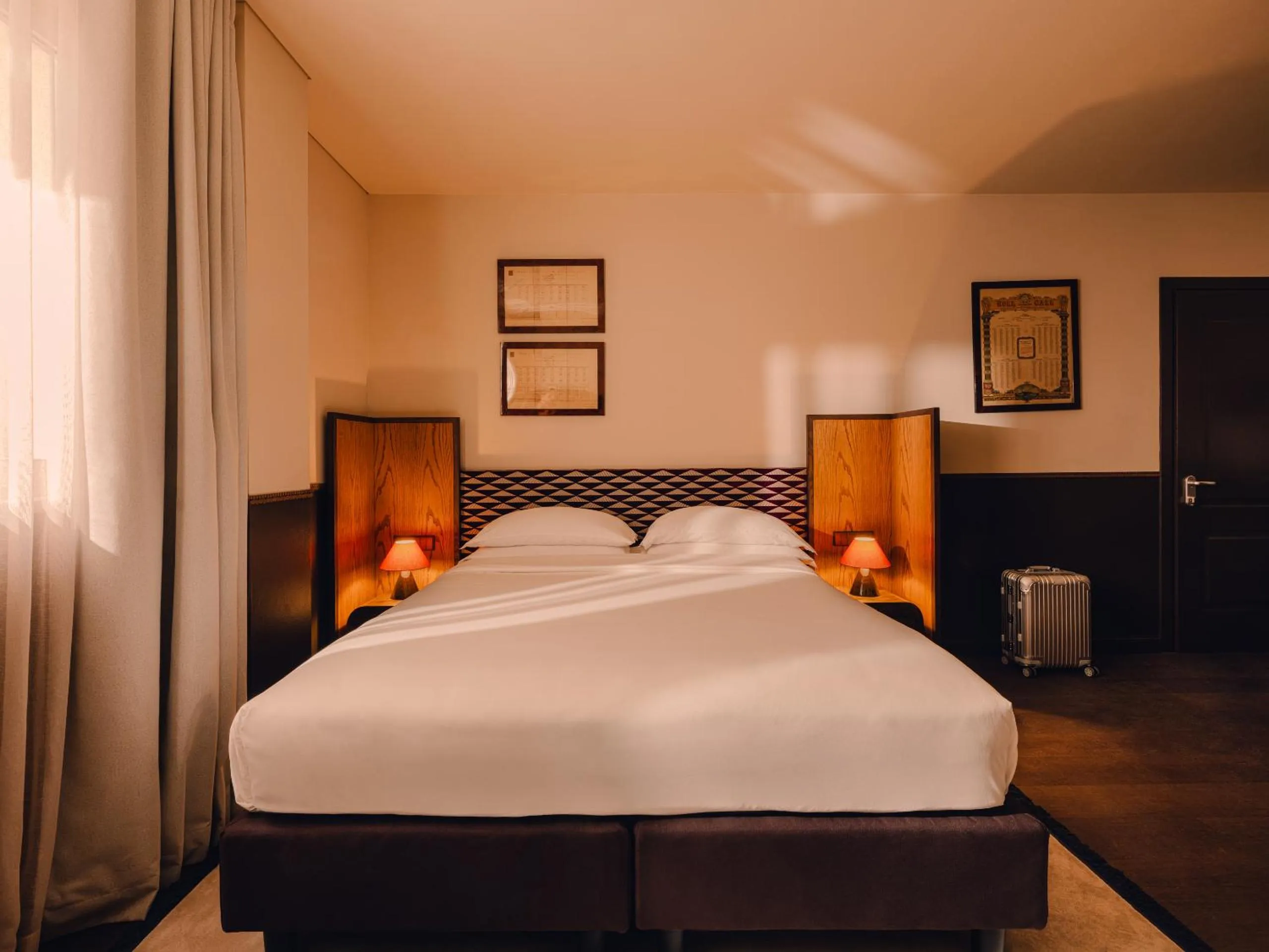 Aethos Milan bedroom with oak headboards, terracotta lampshades and vintage framed prints on cream walls