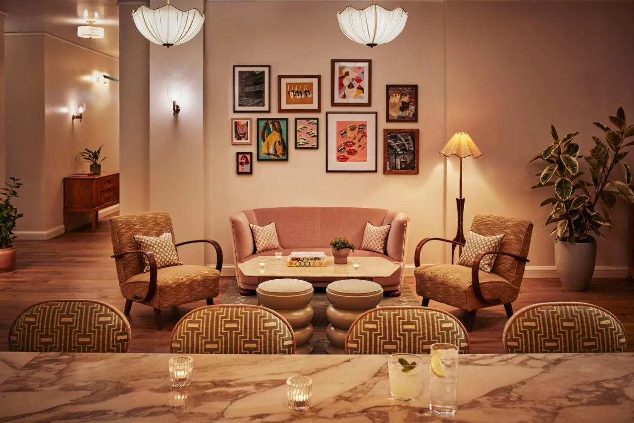 The Hoxton Shepherd's Bush boutique hotel - lobby lounge with blush sofas beneath a gallery wall