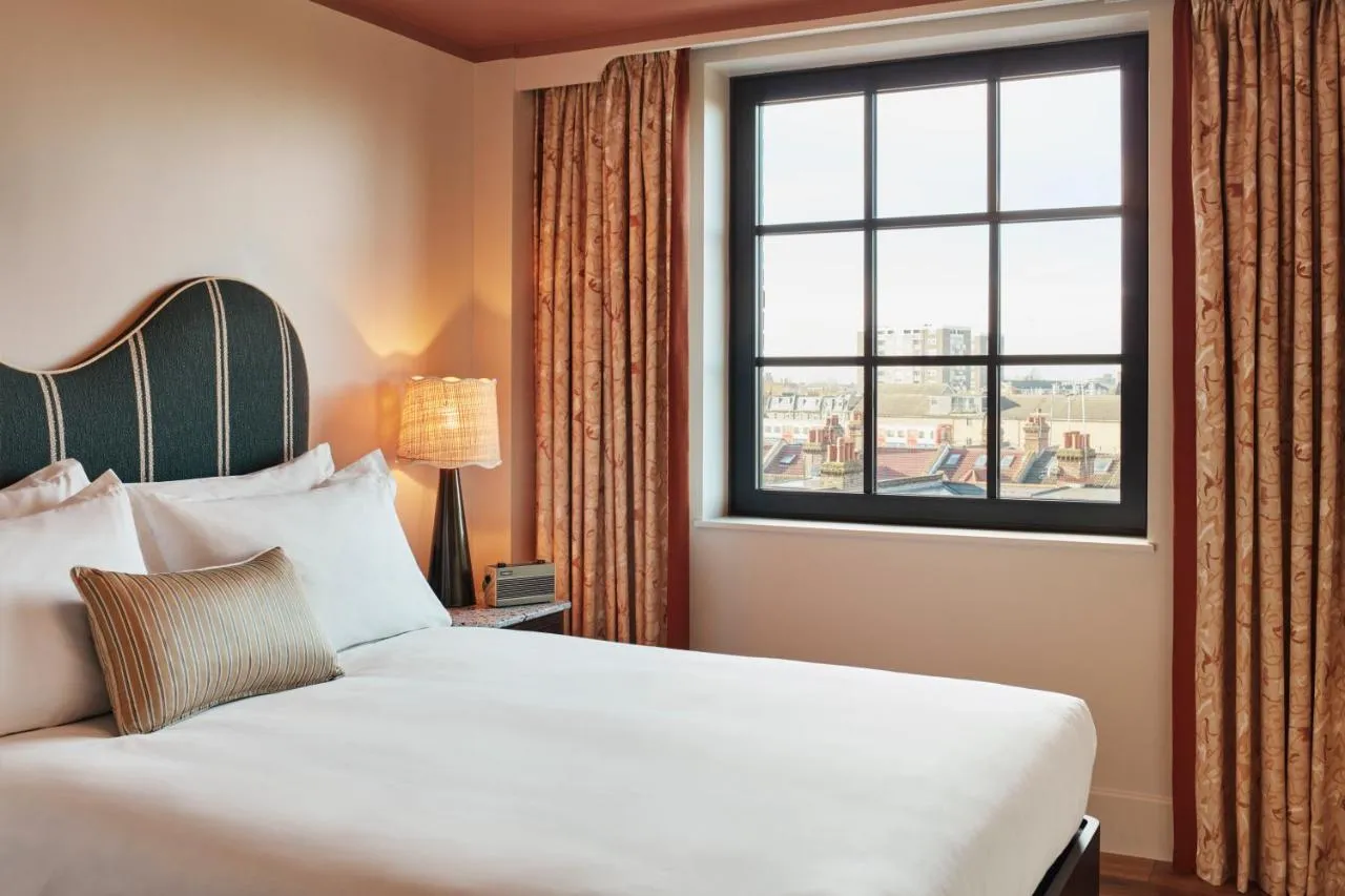 The Hoxton Shepherd's Bush boutique hotel - room with green headboard and a large city-view window