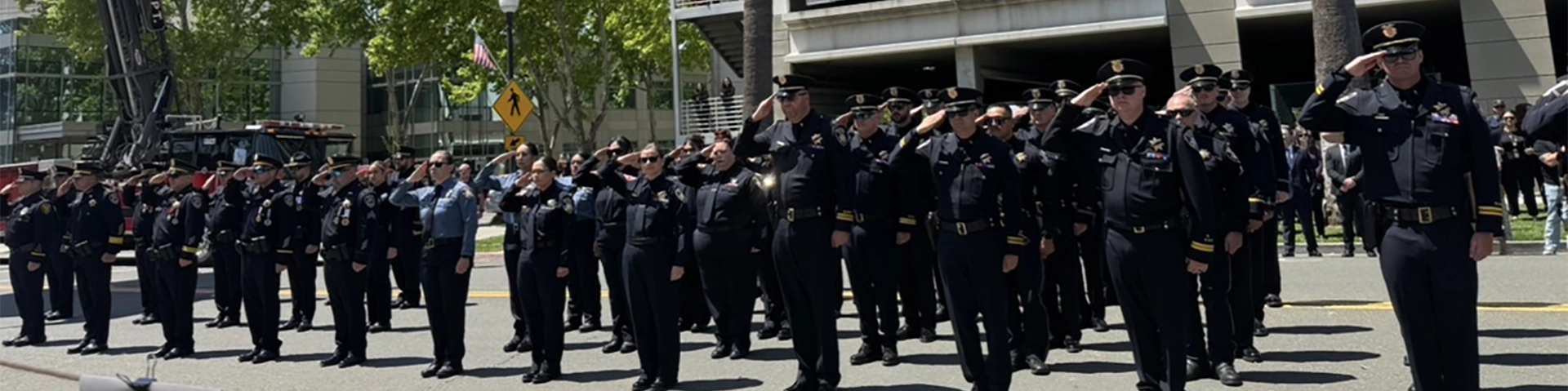 A black and white photo of four firefighters holding a fire hose as it sprays water everywhere.