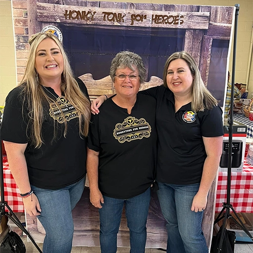 A first responder in fire gear, smiling while sitting on a tree trunk.