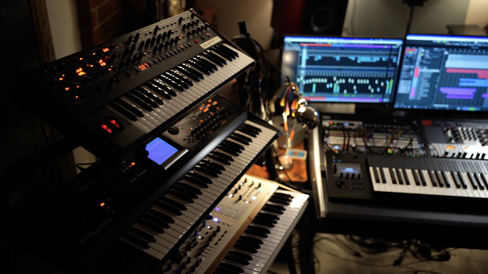 Adam Lukas's studio with hardware synths and a Cubase session on two screens