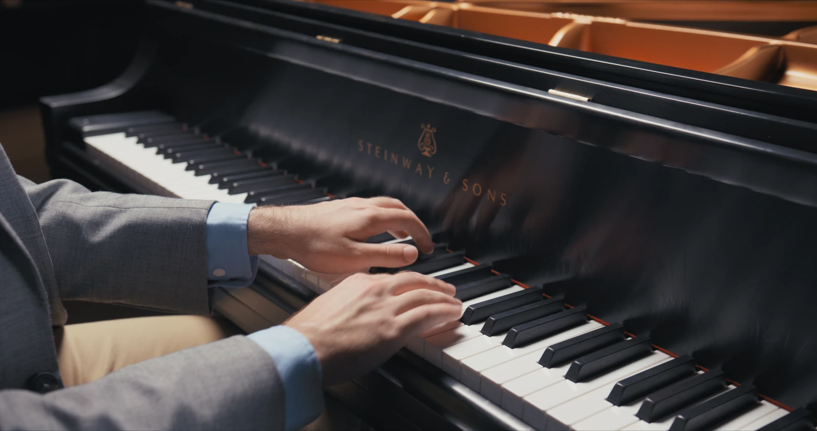 Close-up of two hands playing chords on a grand piano keyboard