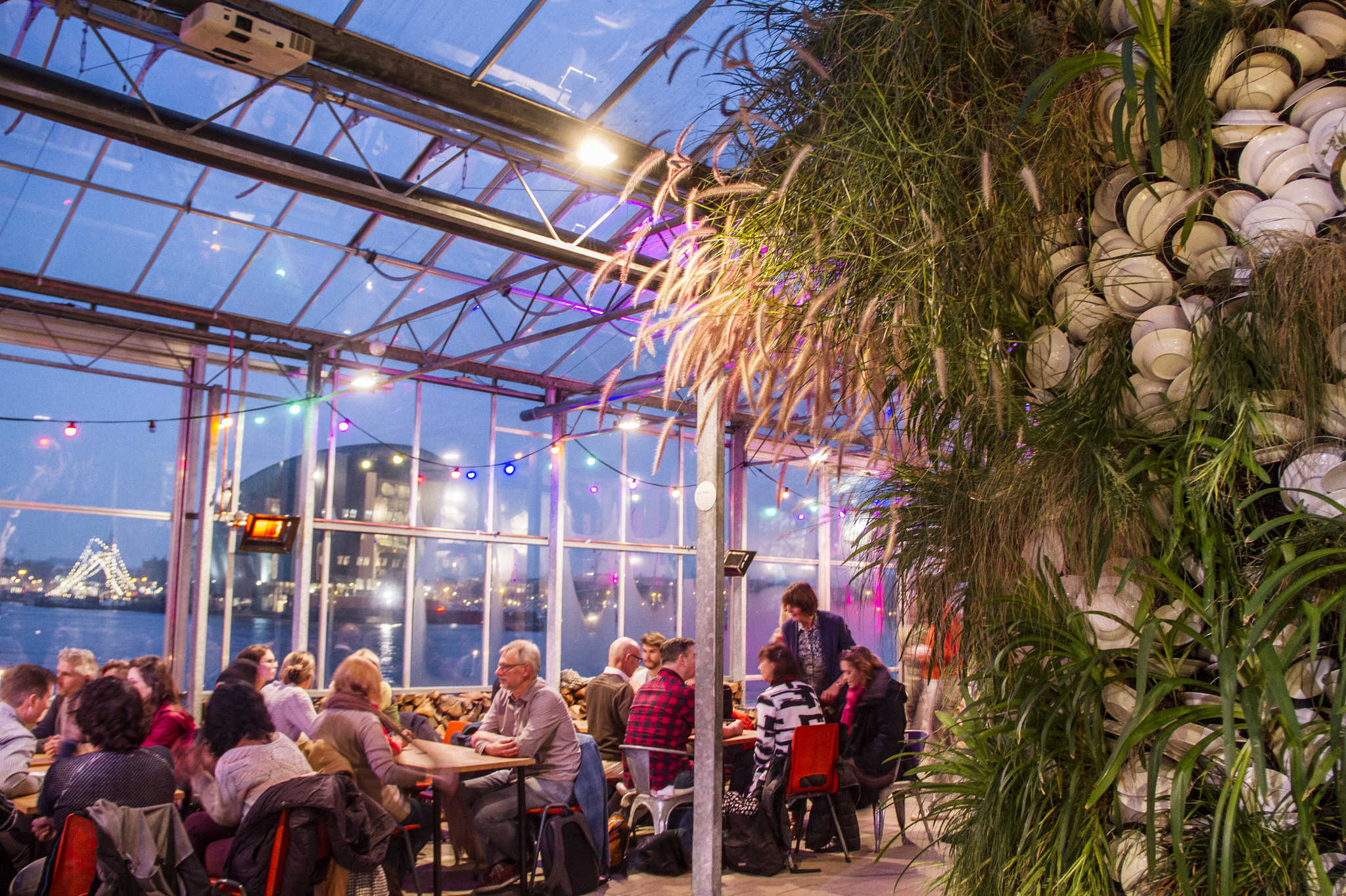 The interior of the restaurant showing people enjoying their meals and green plants surrounding them