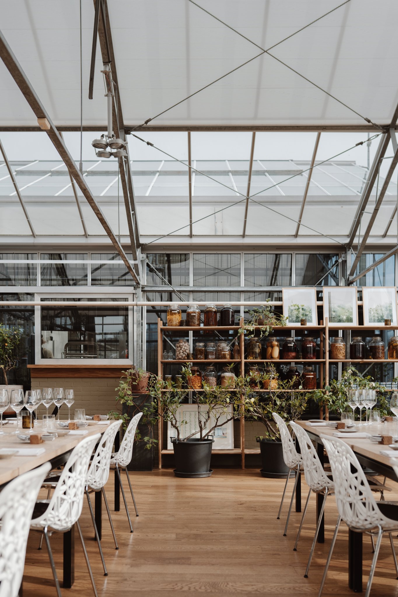 The inside of the restaurant De Kas showing the seats and the beautiful interior using white and wood accents 