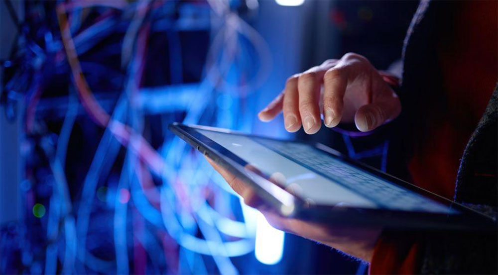 IT technician using a tablet to manage small business network infrastructure in a server room.