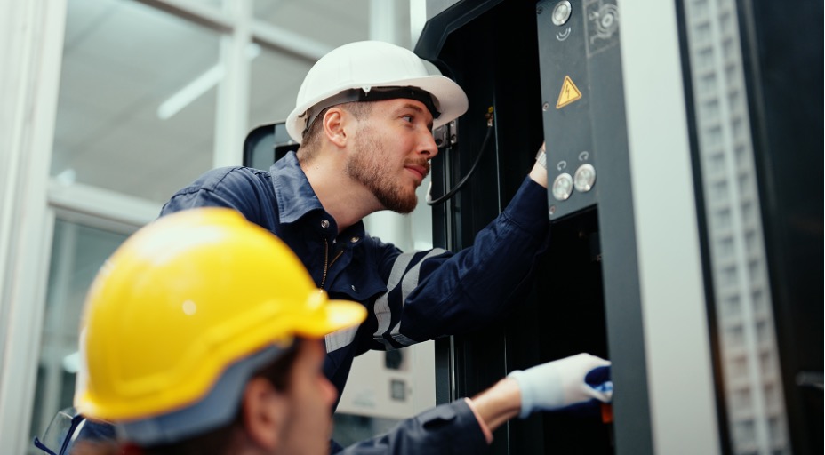 Technicians in hard hats performing IT maintenance on equipment