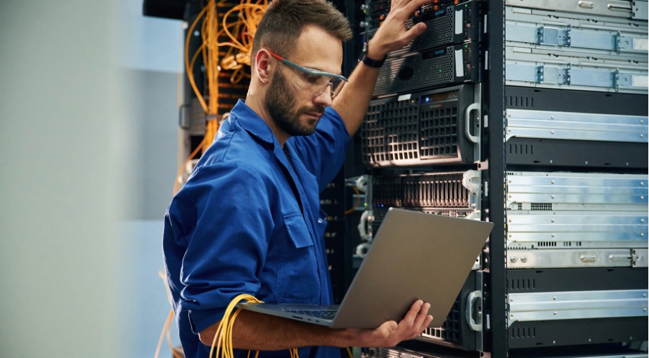 Young man working with internet equipment and wires in server room