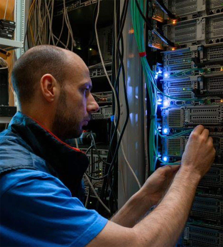 Technician adjusting cables in a data center.