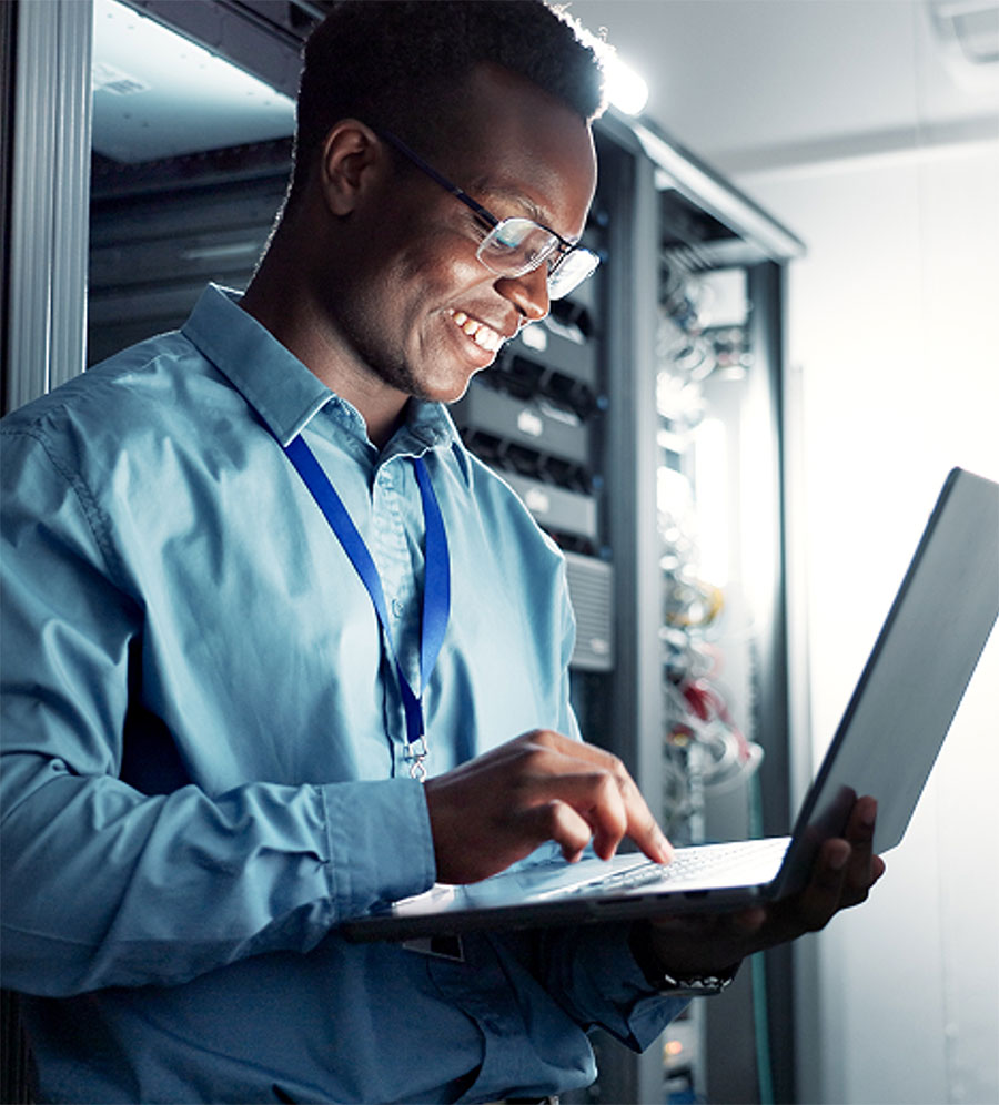 An IT professional typing on a laptop.
