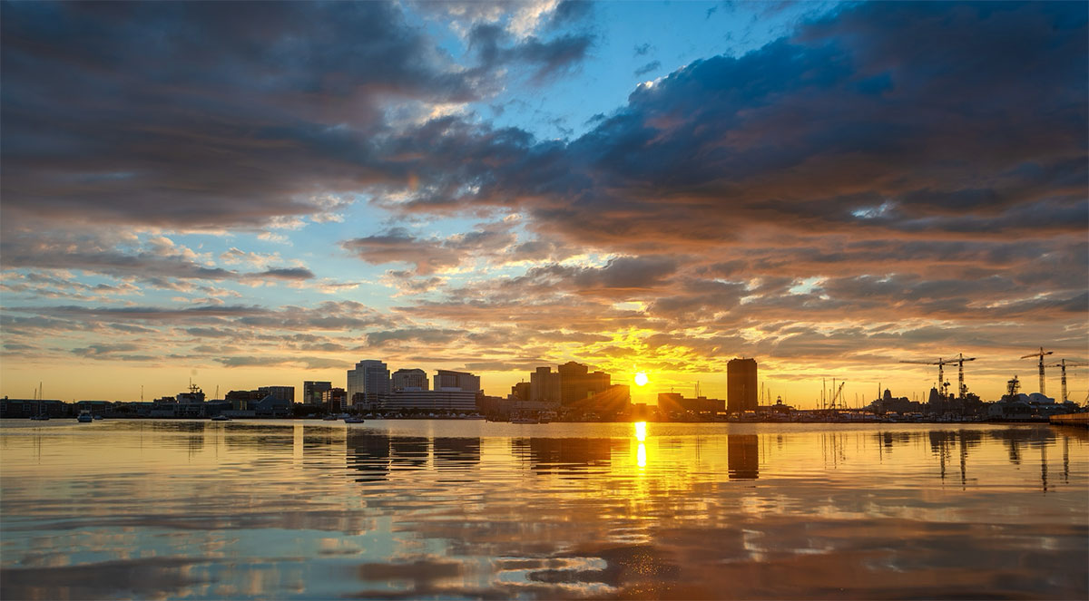 Norfolk, Virginia skyline at sunset reflected on the Elizabeth River, home to First Column IT's managed security services