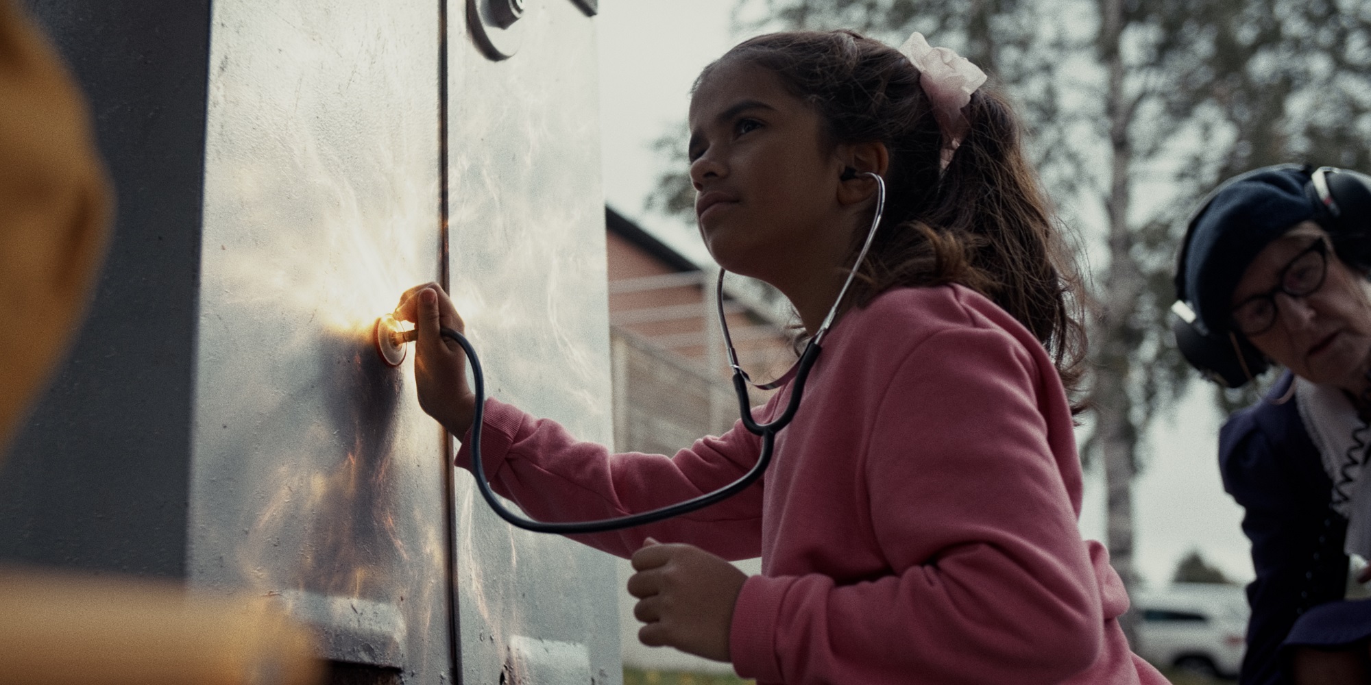 A young girl listens to an electrical cabinet in The Electrical Cabinet