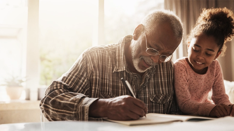 AbbVie Parkinson campaign key visual: an older man writing in a notebook beside his granddaughter