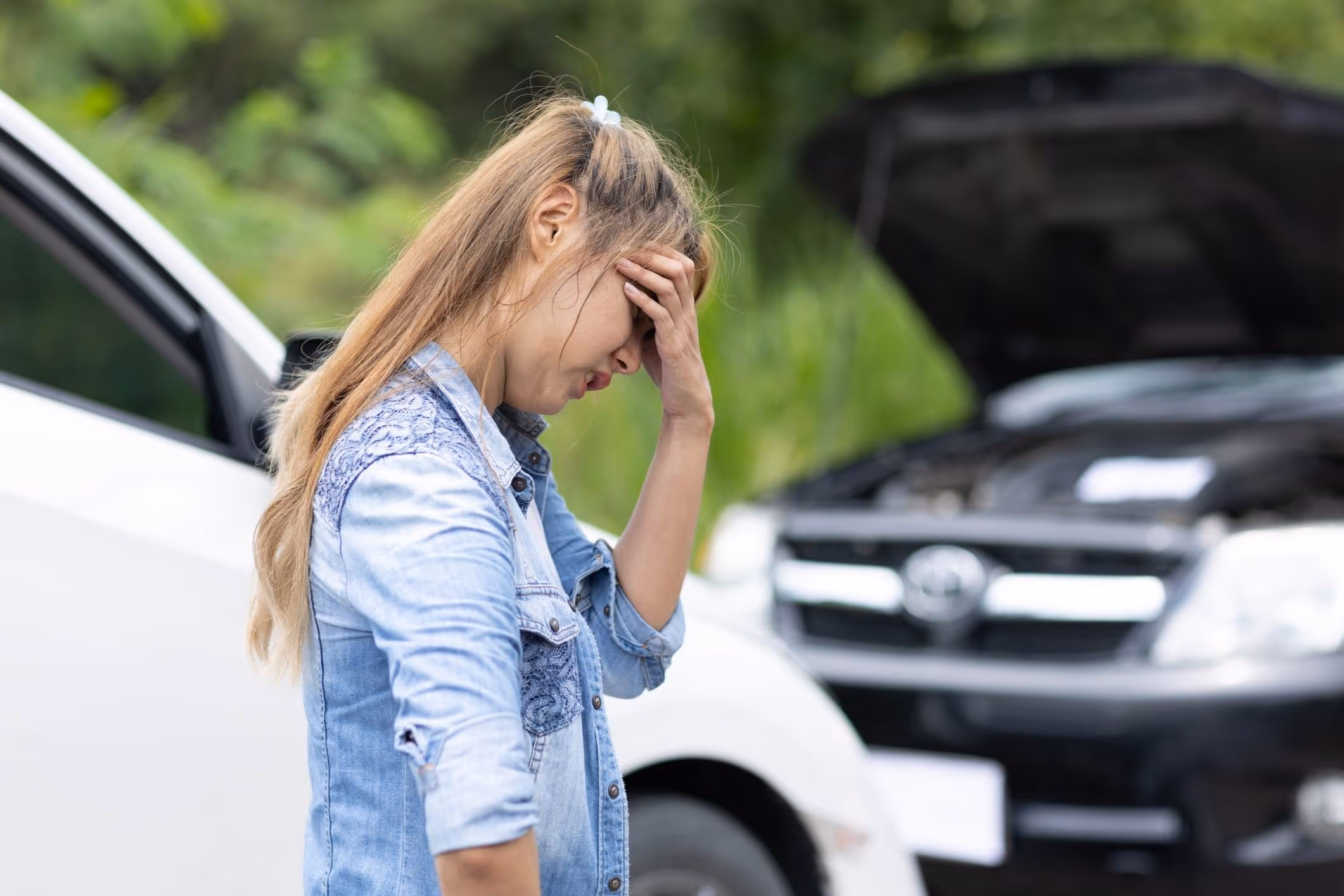 Woman standing beside disabled car, illustrating the need for an Atascocita car accident attorney after a collision.